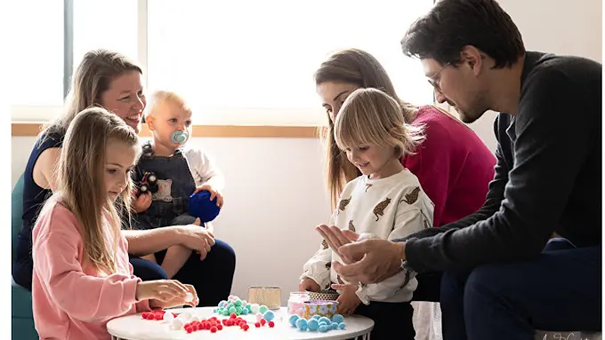 Une famille avec 3 enfants d'âges différents, autour d'une petite table dans le cadre d'un atelier avec la sophrologue.