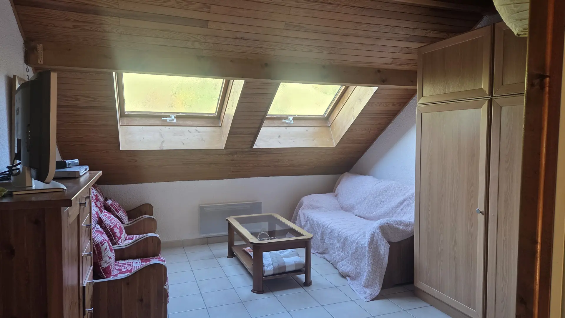 Espace salon avec un canapé lit et 3 fauteuils sous un velux
