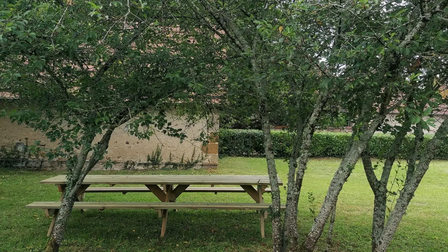 Jardin du gîte avec sa table et ses bancs pour 12 personnes.