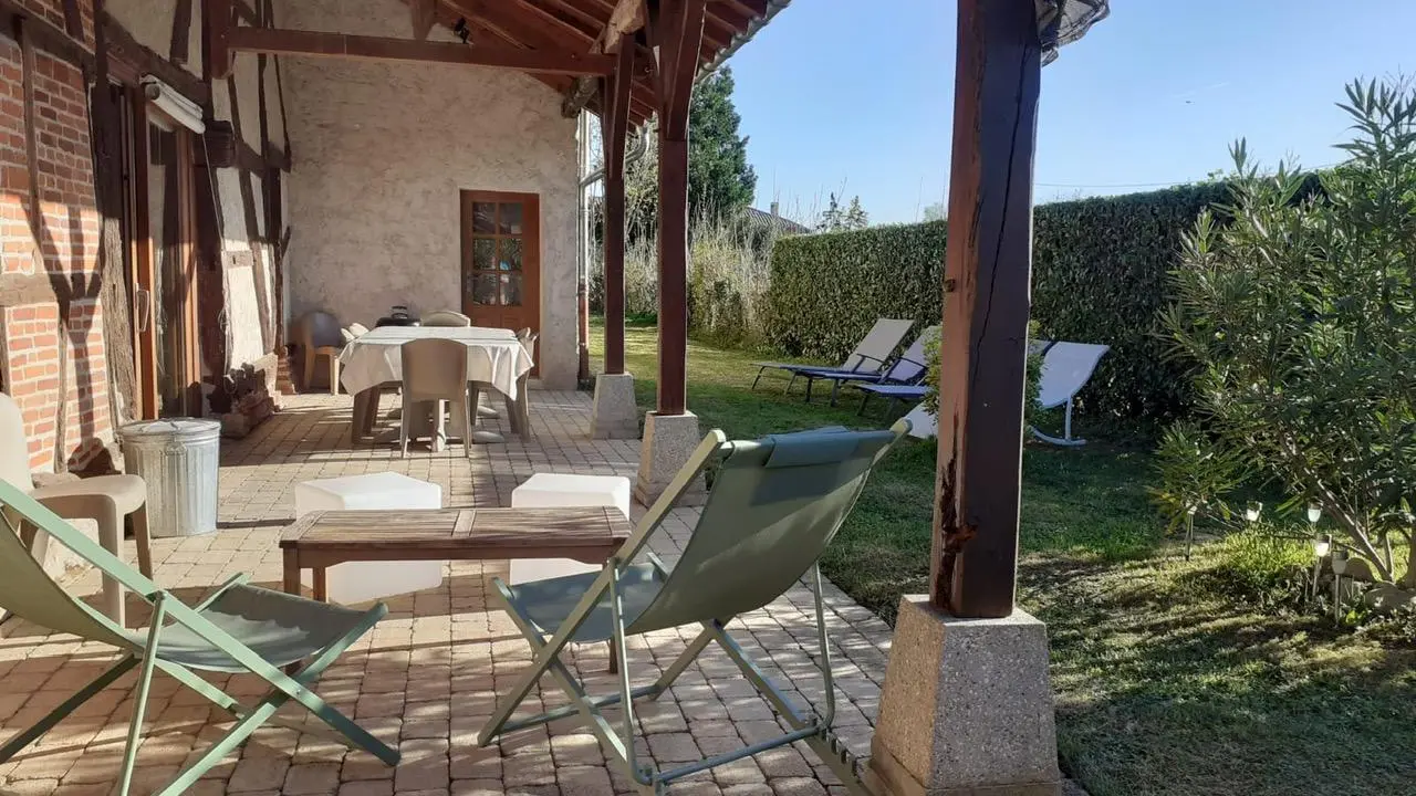 Terrasse couverte à l'arrière de la maison donnant sur un jardin clos