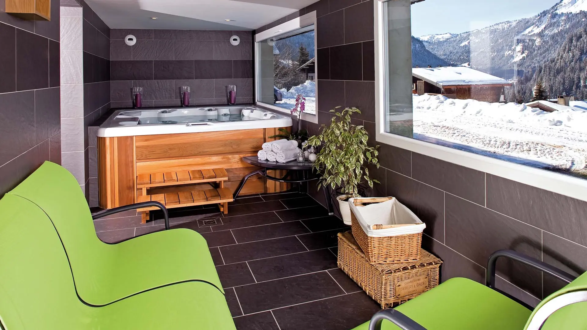 Espace bien-être avec bain à remous, fauteuils et vue sur l'extérieur enneigé