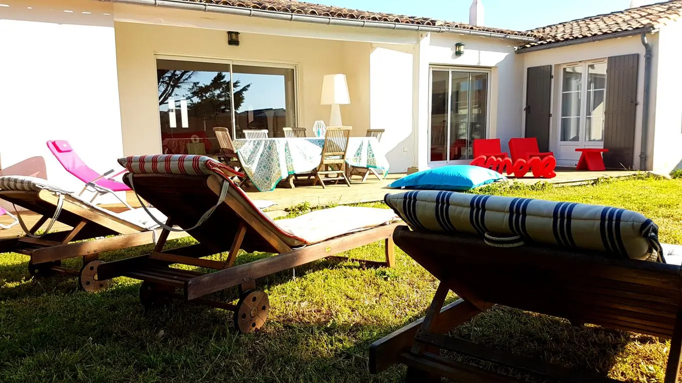 Terrasse et jardin équipés d'une table et de transats