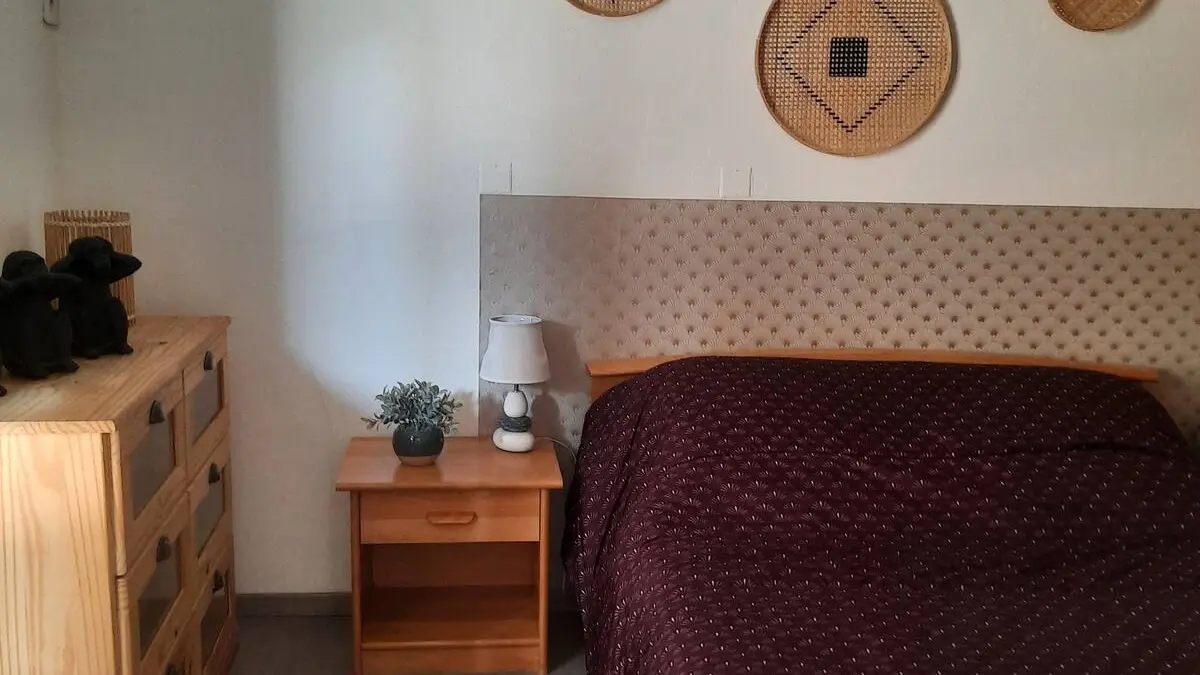 Chambre décoré simplement avec des draps marrons et un mur blanc.