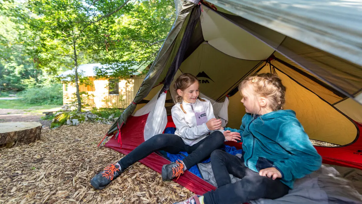 Enfants assis dans une tente avec la cabane à Baban en arrière-plan