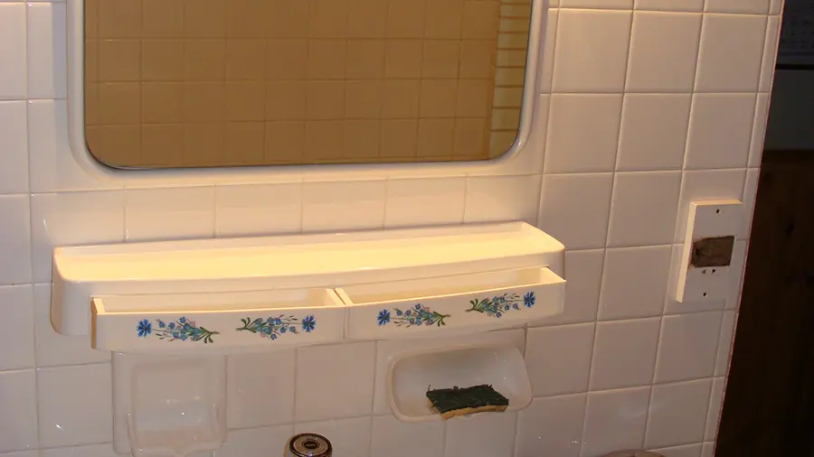 Coin de salle de bains avec évier, miroir, mur et sol carrelés