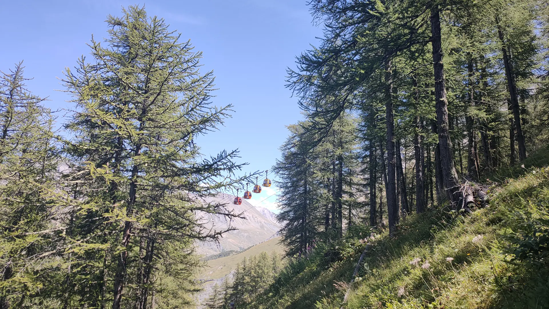 Les télécabines qui passent au dessus du chemin avec un randonneur