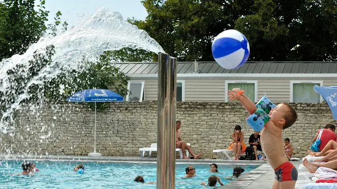 Enfant jouant au ballon au bord de la piscine