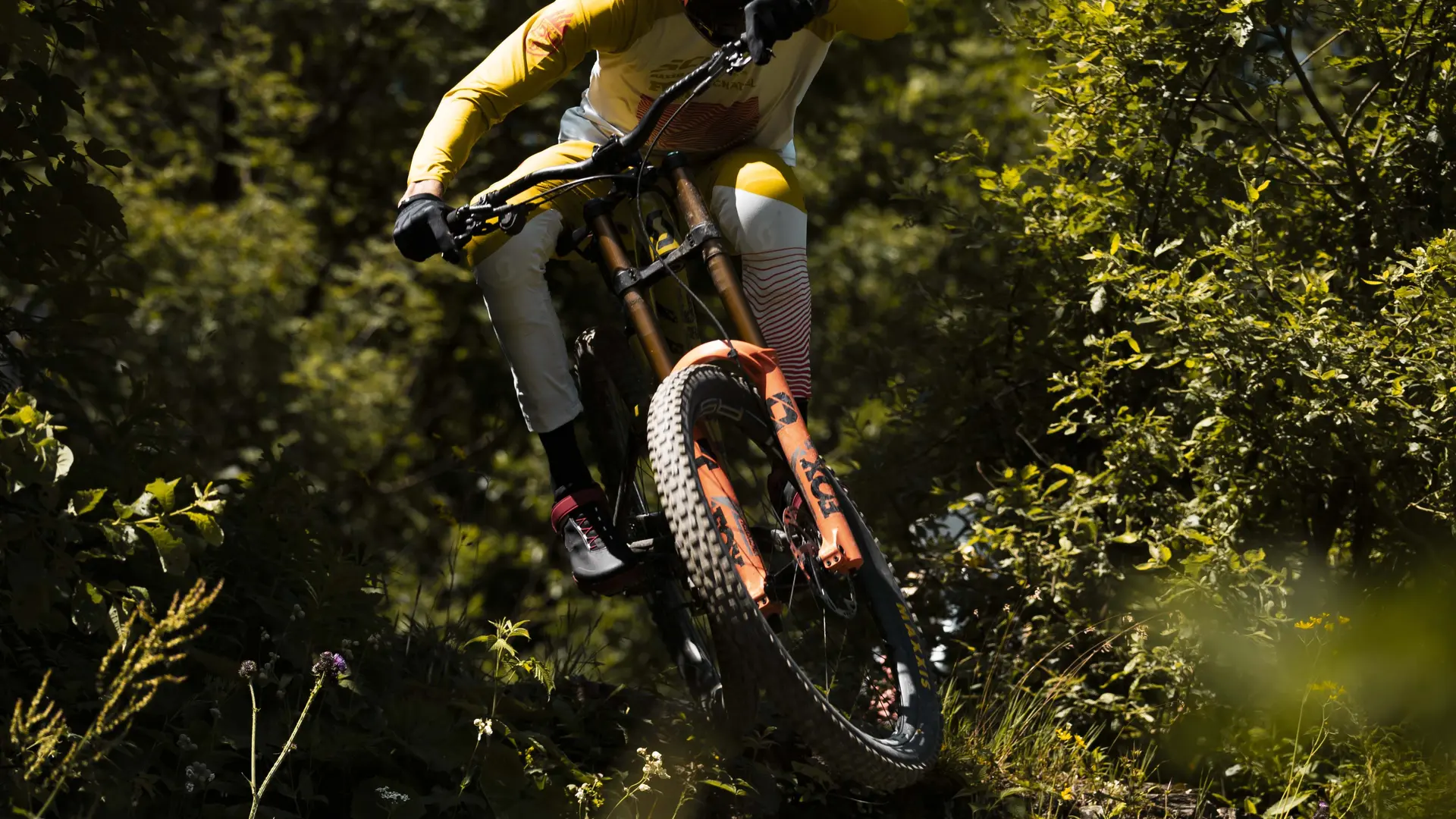 Vététiste en plein saut dans la piste noire Dré dans l'pentu du bike park de Châtel
