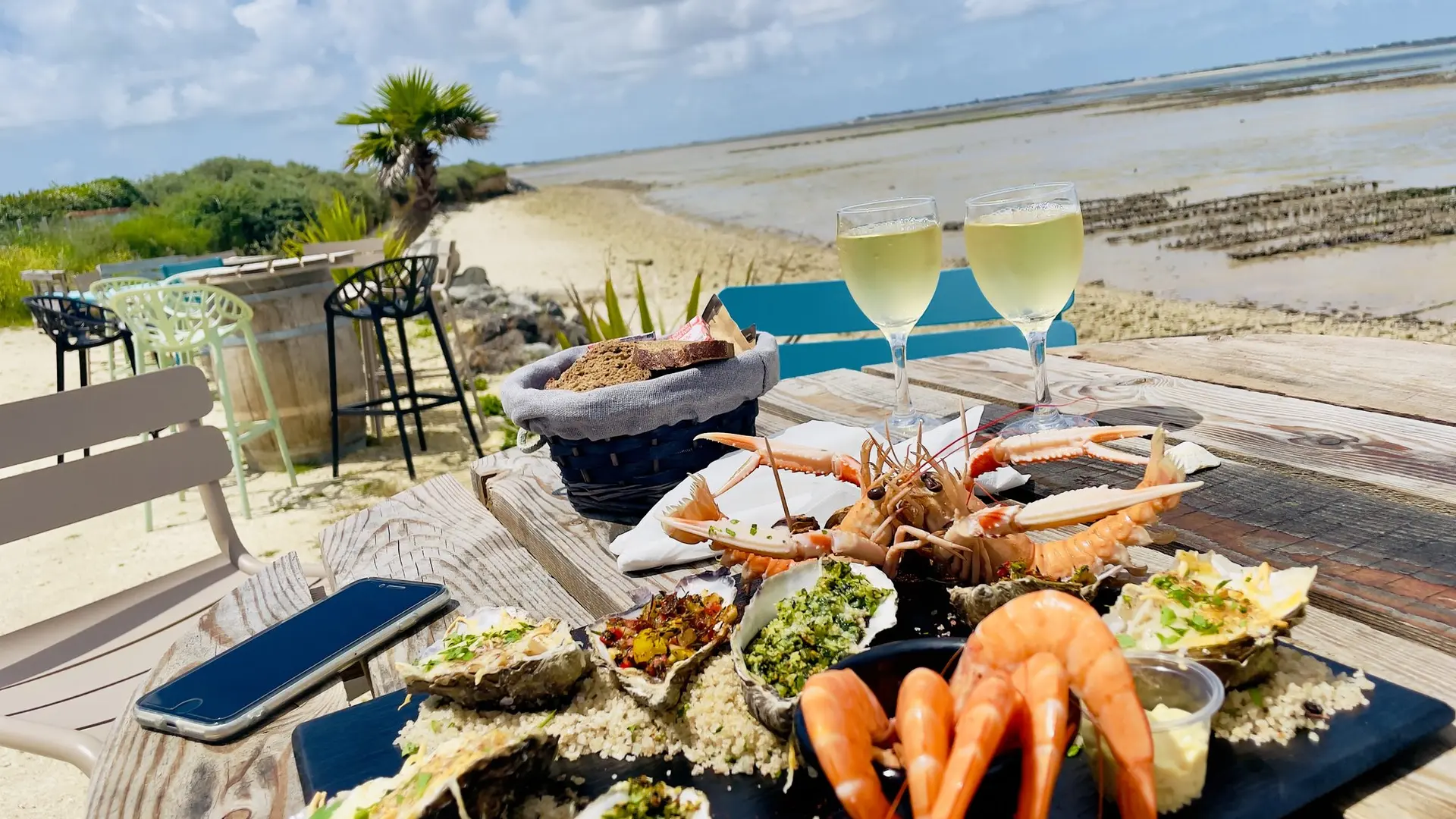 Assiette avec crevettes, huîtres, langoustines. + verres de vin et vue mer