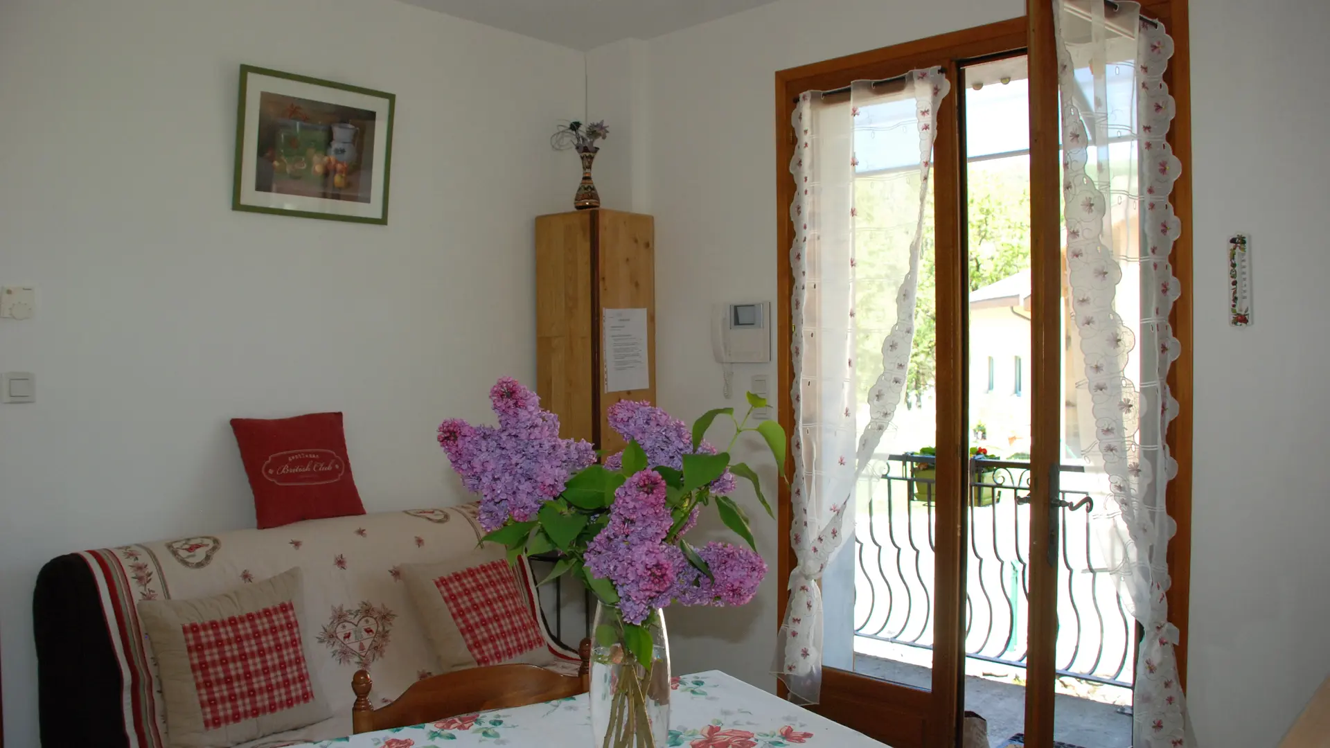 Cette pièce combine un coin salon équipé d'un canapé et une salle à manger avec une table. Des portes-fenêtres offrent une vue sur l'extérieur.