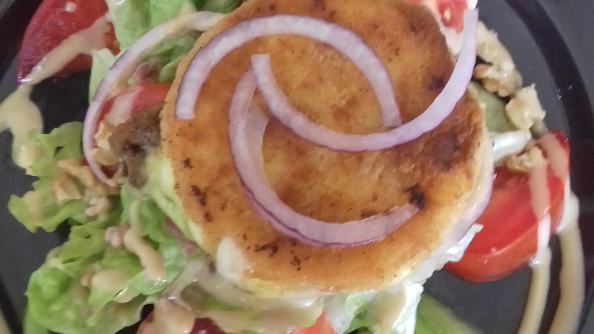 Une revisite du fromage le Saint-Marcellin, il est pané et présenté sur une salade verte , tomates, oignons et noix.