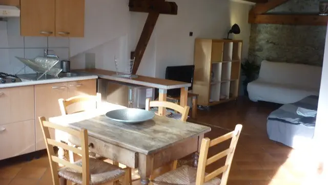 Cette cuisine est équipée d'éléments bas et hauts, d'un évier, d'une plaque de cuisson à gaz et d'une table avec quatre chaises.