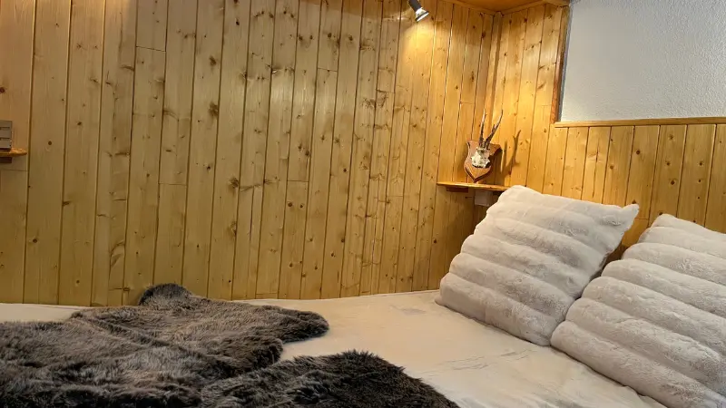 Bedroom with double bed, wood paneling wall, high cupboard
