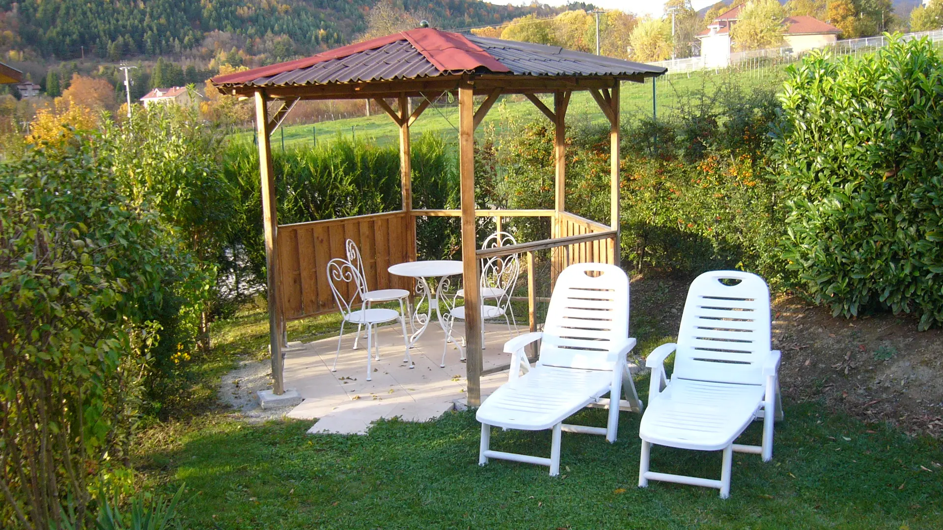 Le jardin possède deux transats et une tonnelle avec une table en fer forgé et quatre chaises.