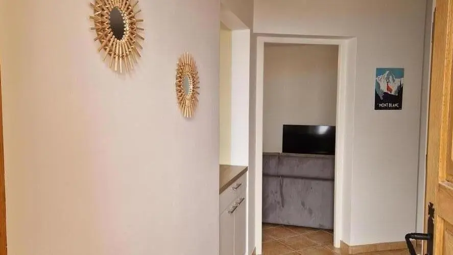 Couloir avec accès cuisine/séjour (gauche) et chambre + pièces d'eau (droite)