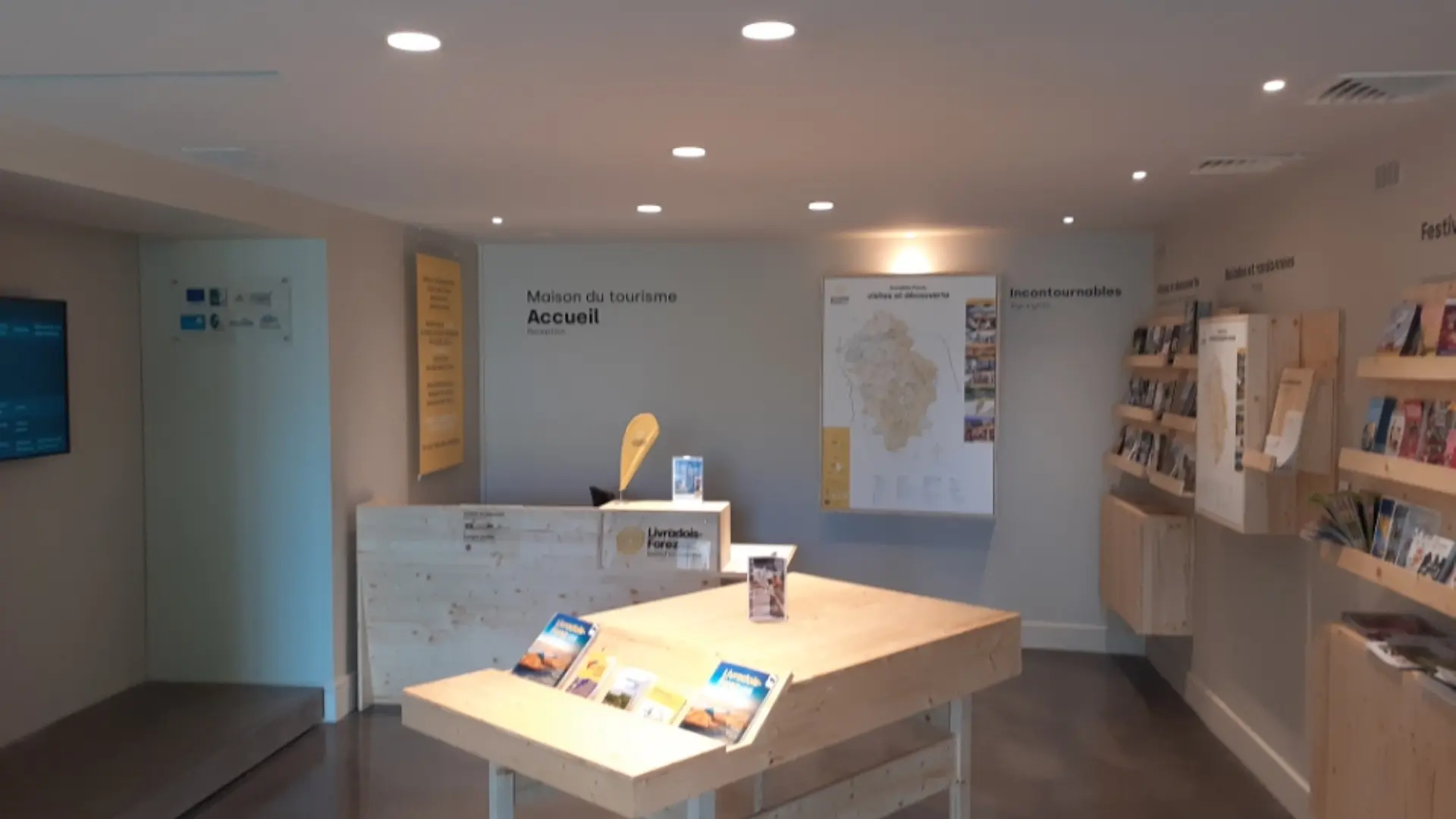 Espace d'accueil très aéré avec en son centre le piano pour échanger avec le conseiller en séjour et sur les côtés la carte touristique et de randonnée ainsi que les présentoirs en bois de notre région. Au fond de l'accueil se trouve le comptoir !