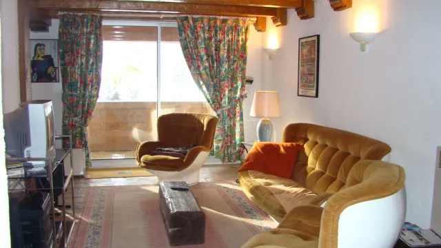 Séjour lumineux avec canapé, fauteuils, TV, tapis, porte-fenêtre