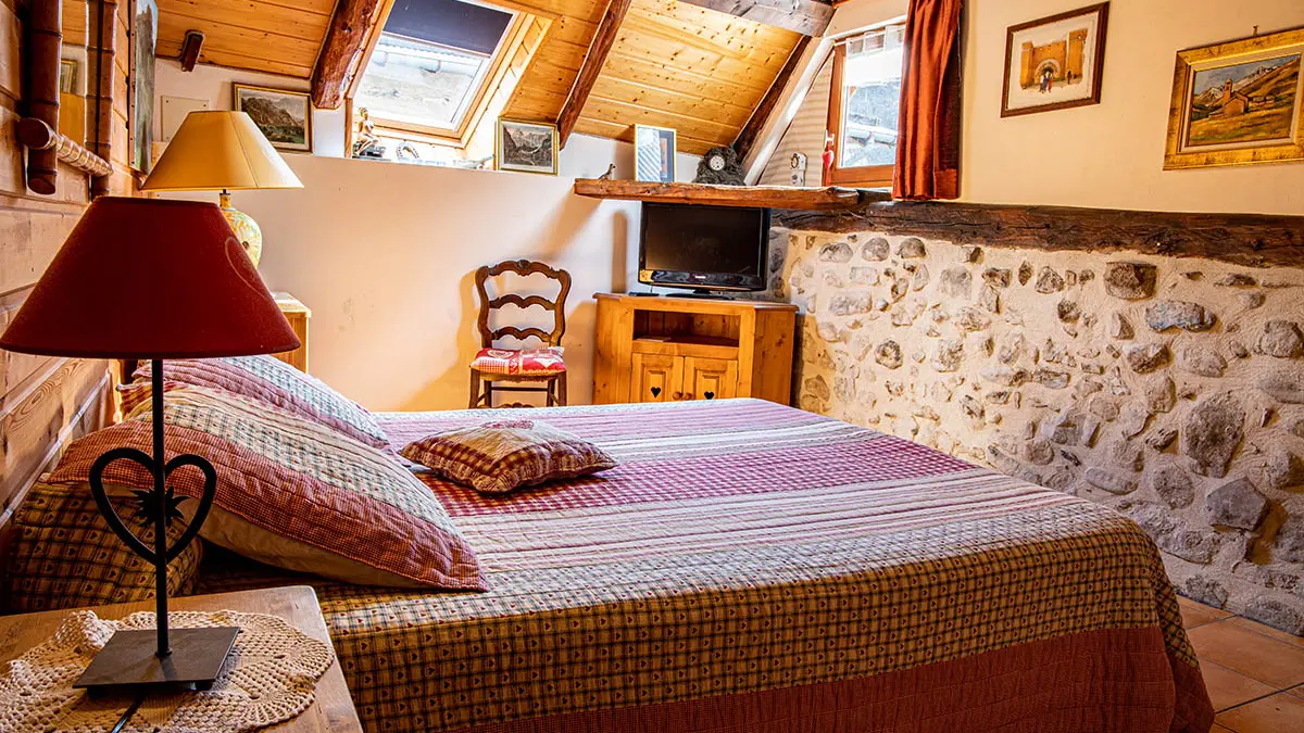 Bright and cozy attic bedroom with double bed, wooden indoor furniture and windows