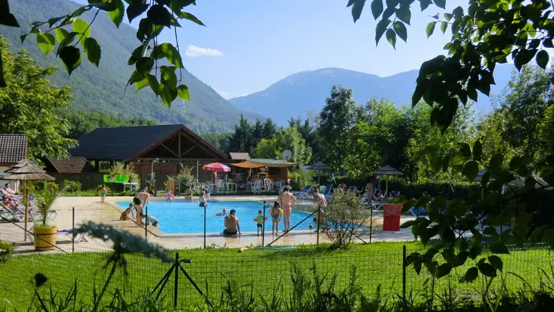 Une piscine rectangulaire est nichée au cœur d'un espace vert, avec en toile de fond une chaîne de montagnes.