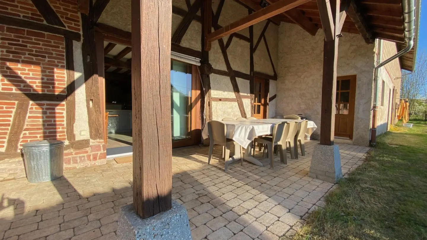 Terrasse couverte à l'arrière de la maison donnant sur un jardin clos
