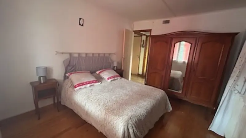 Bright room with wooden flooring and double bed. Tree door wardrobe with a mirror in the center