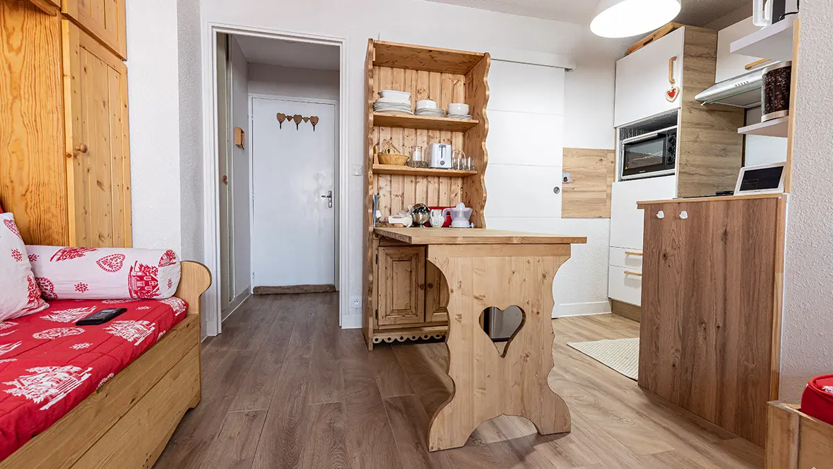 Studio apartment living room with sofa bed, dining table, kitchenette, wooden furniture, door to other spaces