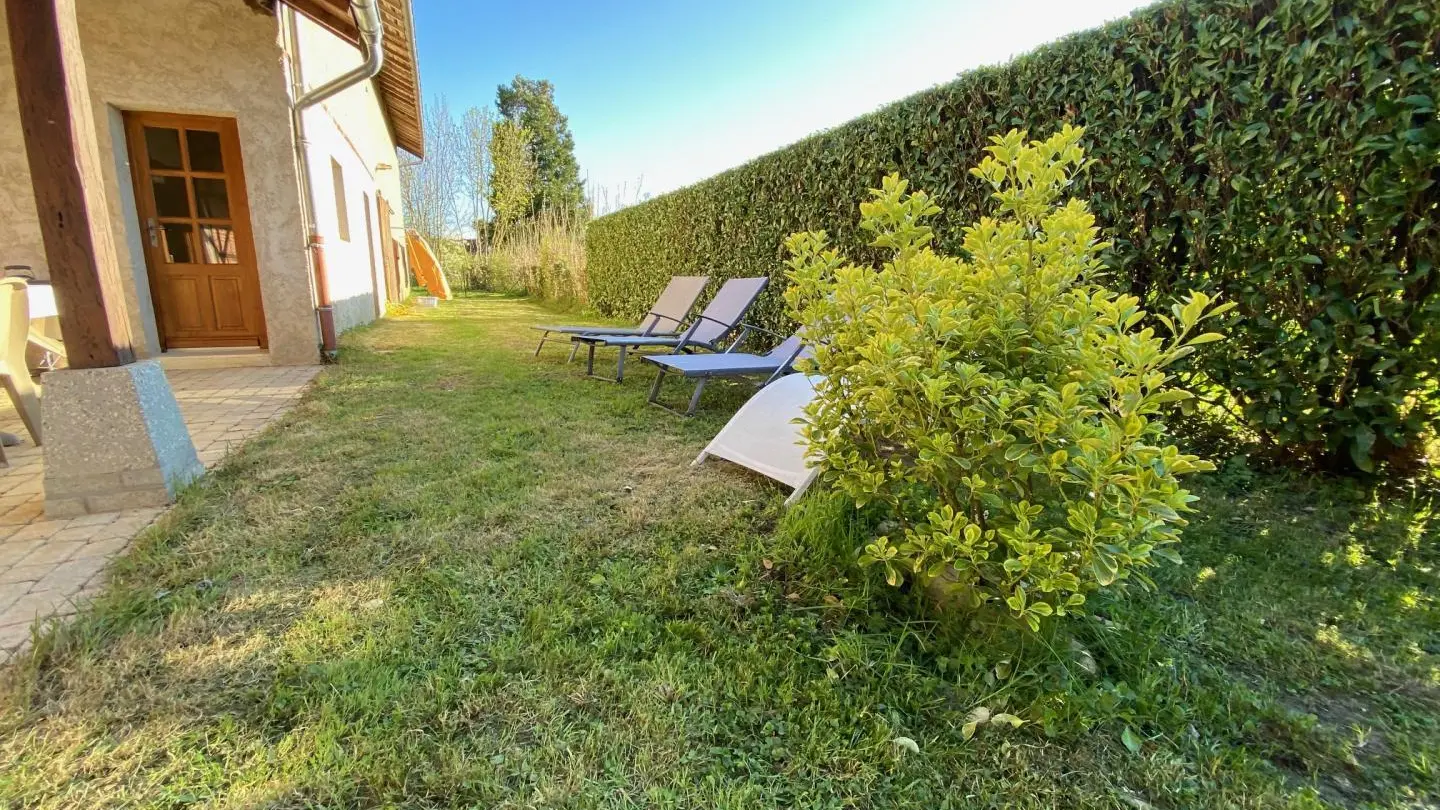 Terrasse couverte à l'arrière de la maison donnant sur un jardin clos