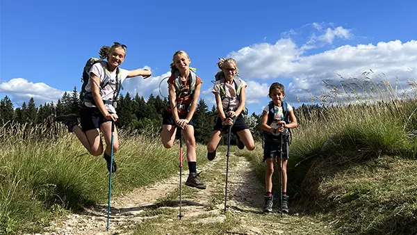 4 randonneurs sur une piste dans une prairie sautant en l'air