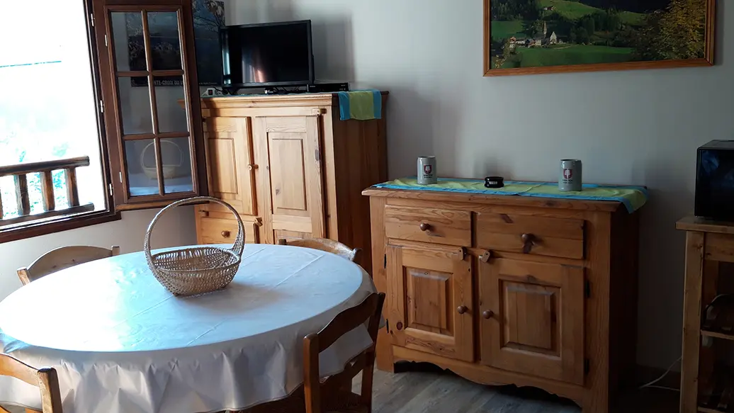 Bright living room with dining table, TV, wood furniture, parquet flooring, window overlooking the mountains