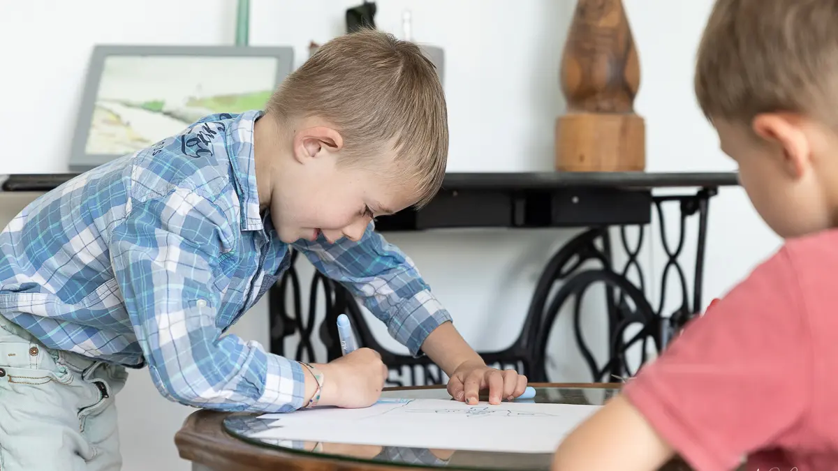 Deux enfants dessinant sur une petite table basse.