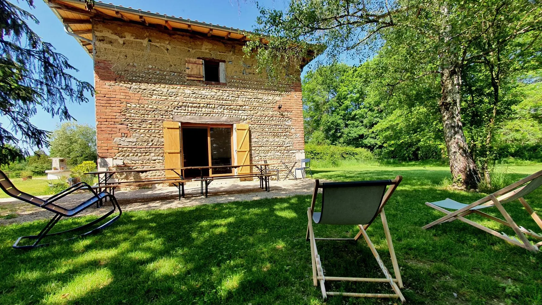 Vue sur l'entrée et la terrasse ombragée exposée plein sud