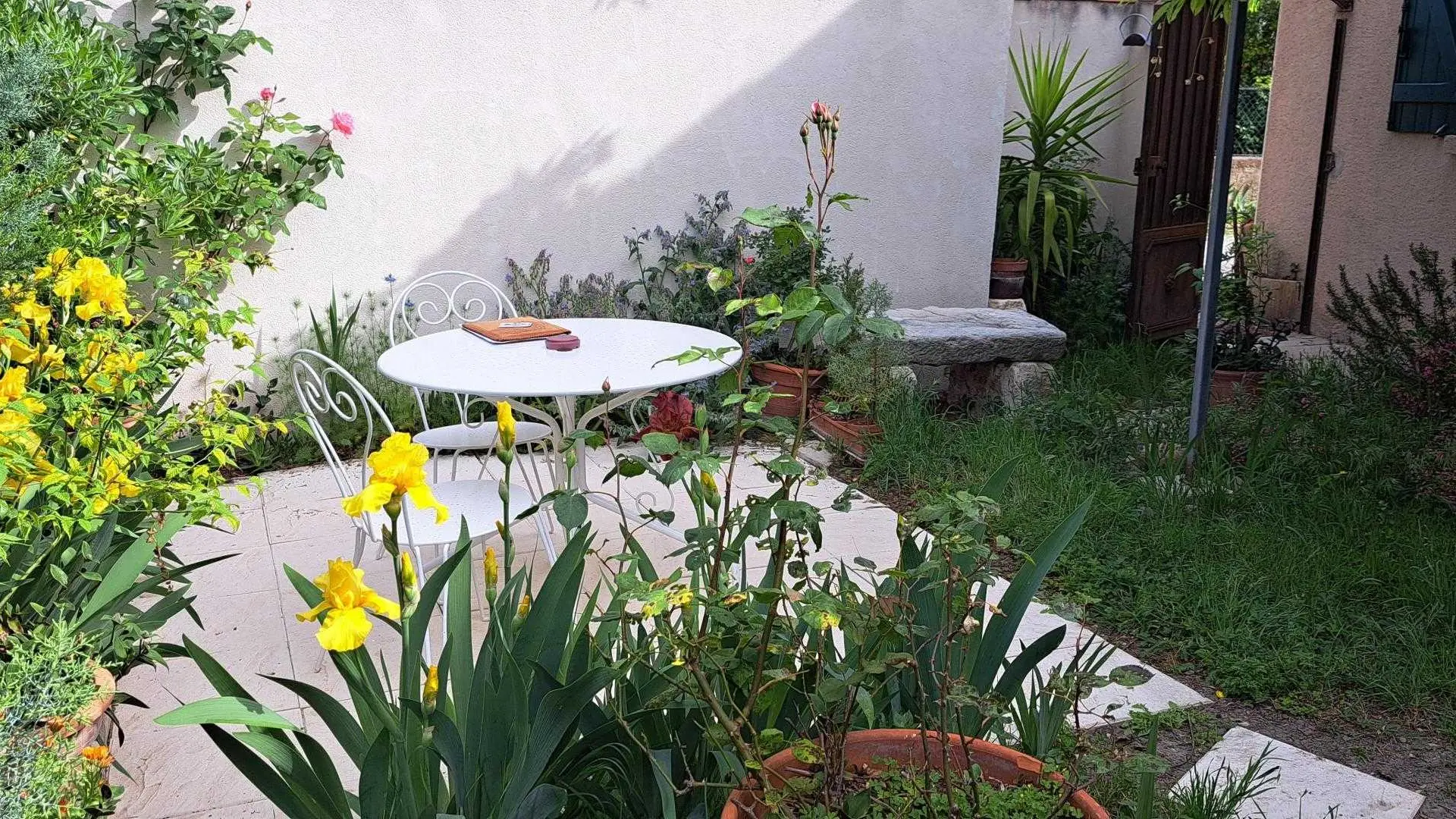 Terrasse jardin en fleurs dans la cour de l'Oustau dei Aucèus.