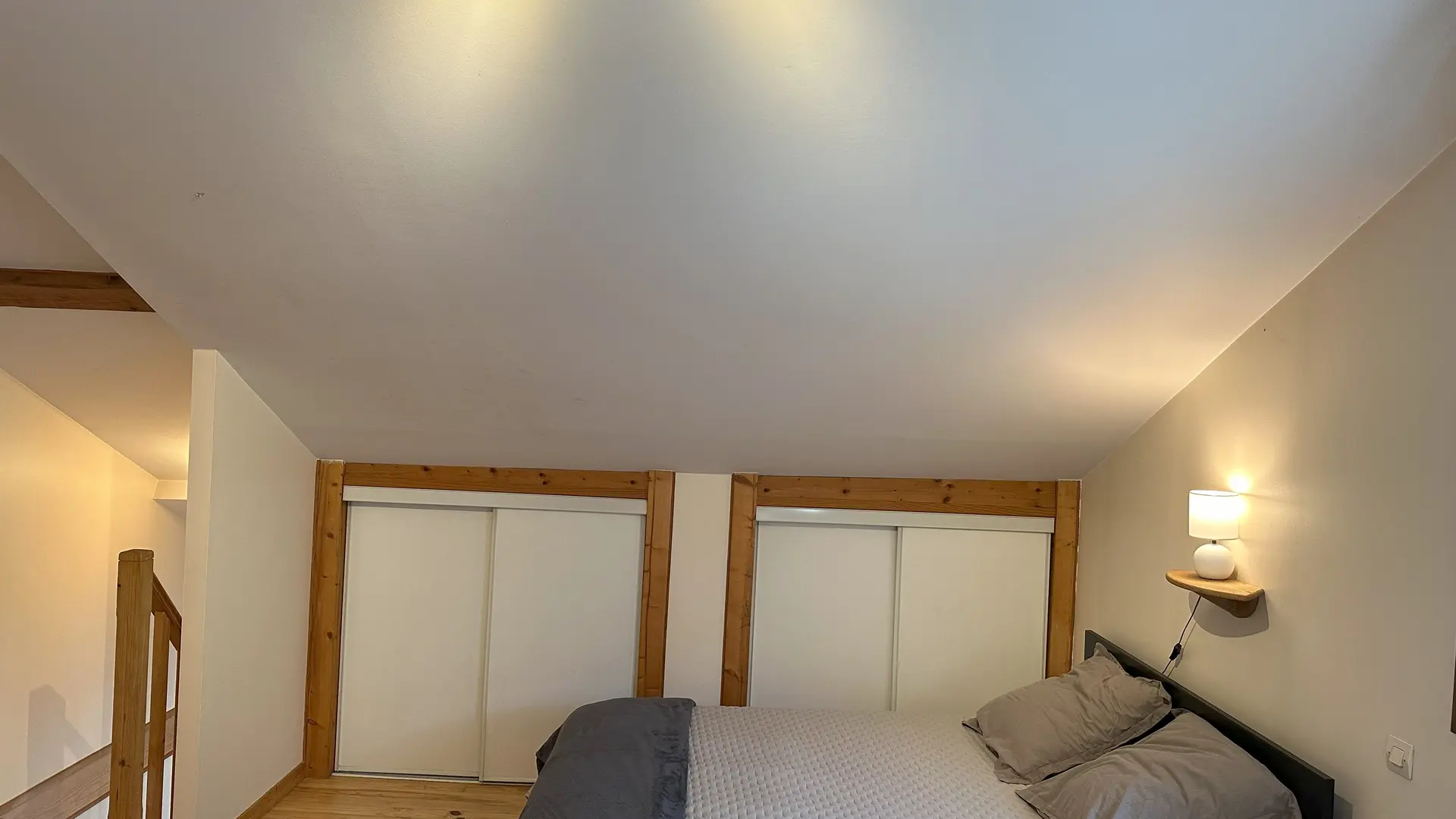 Cette chambre mansardée est lumineuse. Elle dispose d'un grand lit double. Le sol est en bois et les murs sont de couleur claire. Des portes coulissantes donnent sur deux placards encastrés dans une sous-pente.