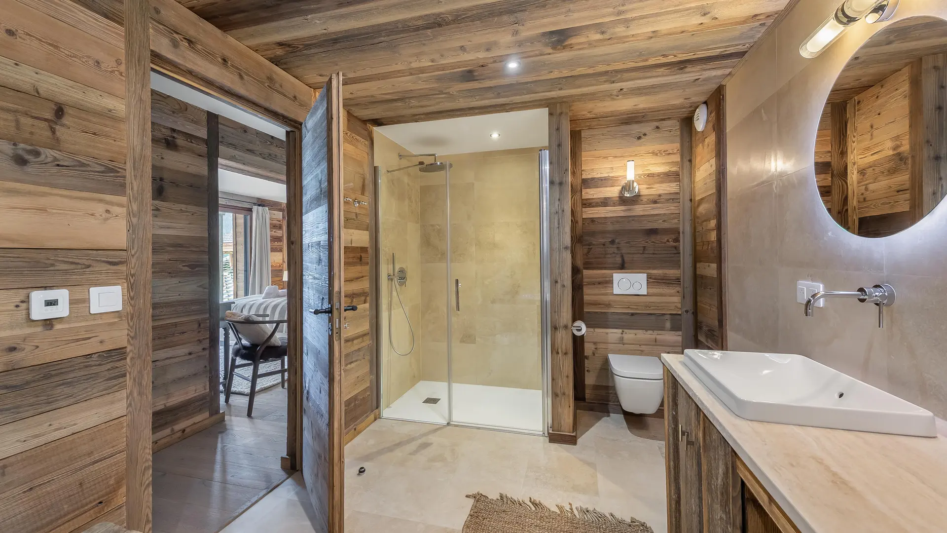Salle de bains avec douche, toilettes, double vasque, miroir, murs et plafond en bois