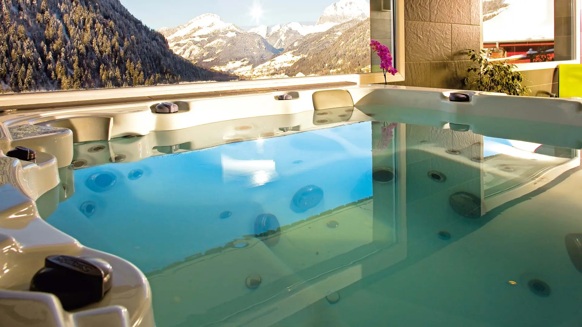 Zoom sur le bain à remous avec vue sur les montagnes ennéigées grace aux grandes fenêtres