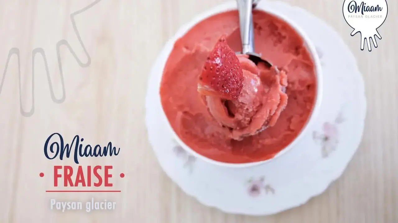 Une boule de sorbet fraise dans une coupelle décorée.