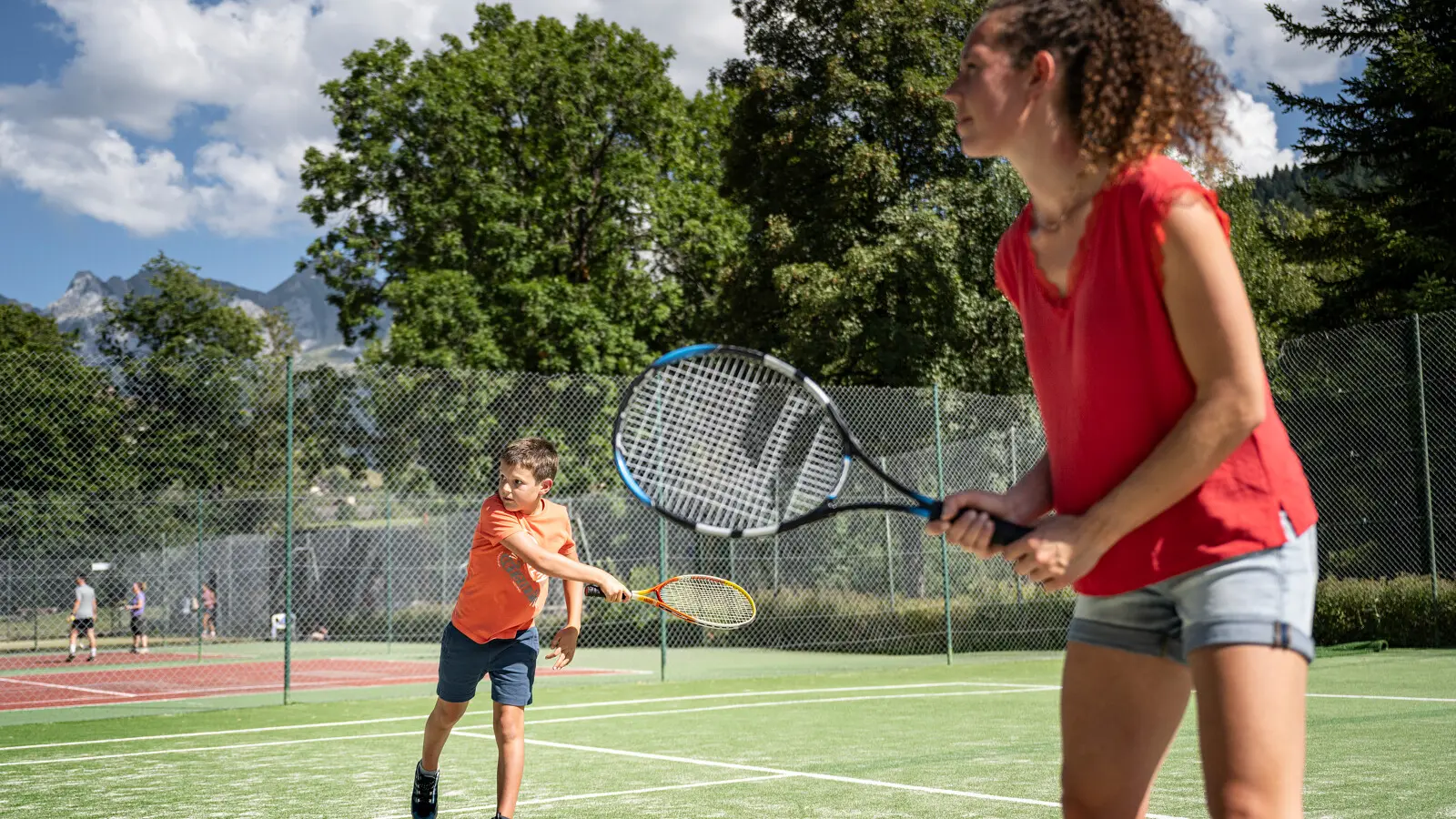 photo d'un enfant et d'une femme en train de jouer au tennis