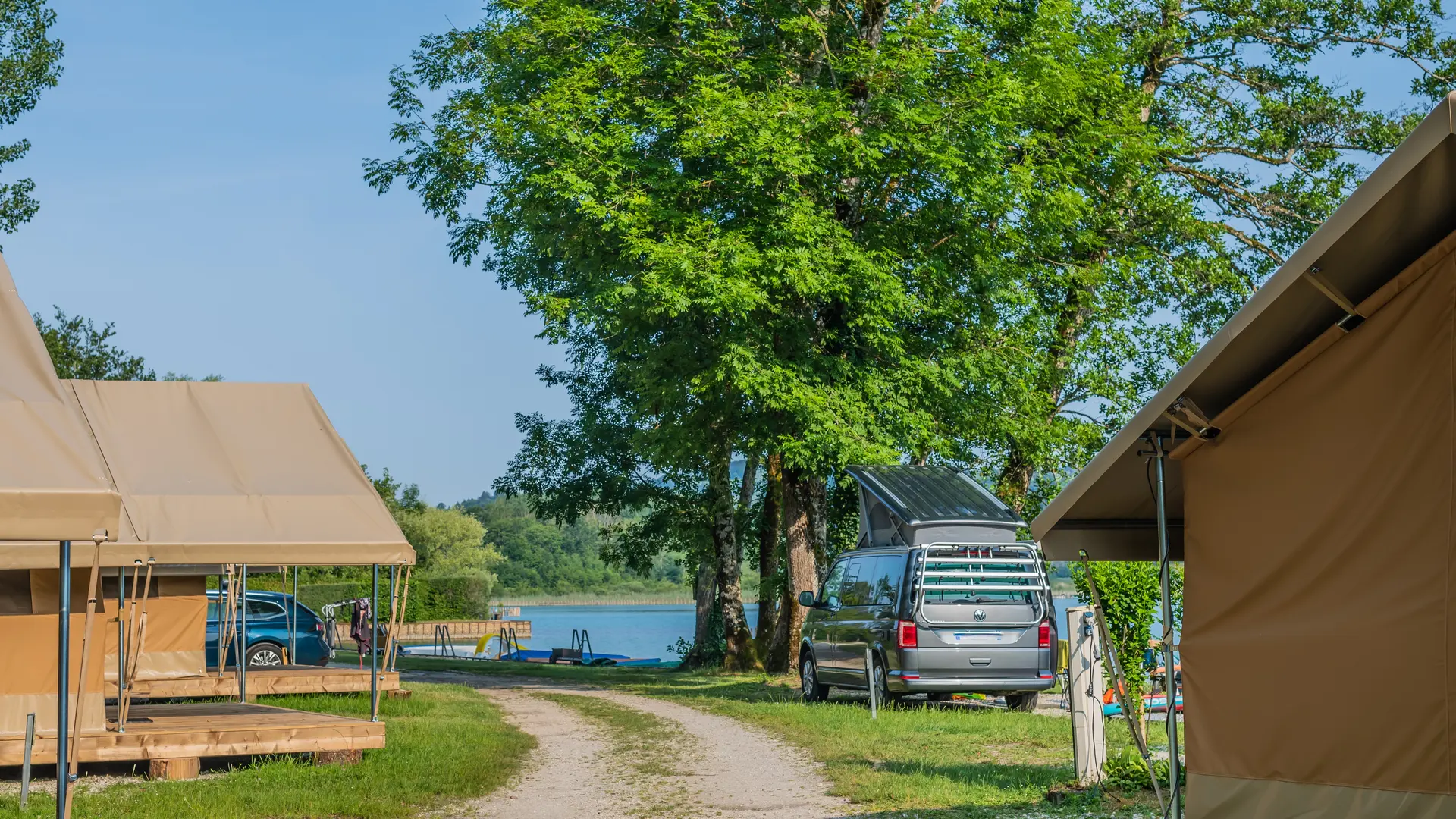 Allée principale camping avec chalet et accès lac