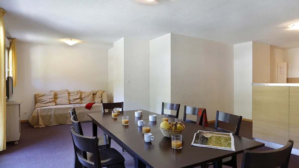 Salon d'appartement avec table à manger, canapé, TV, ameublement bois, fenêtre