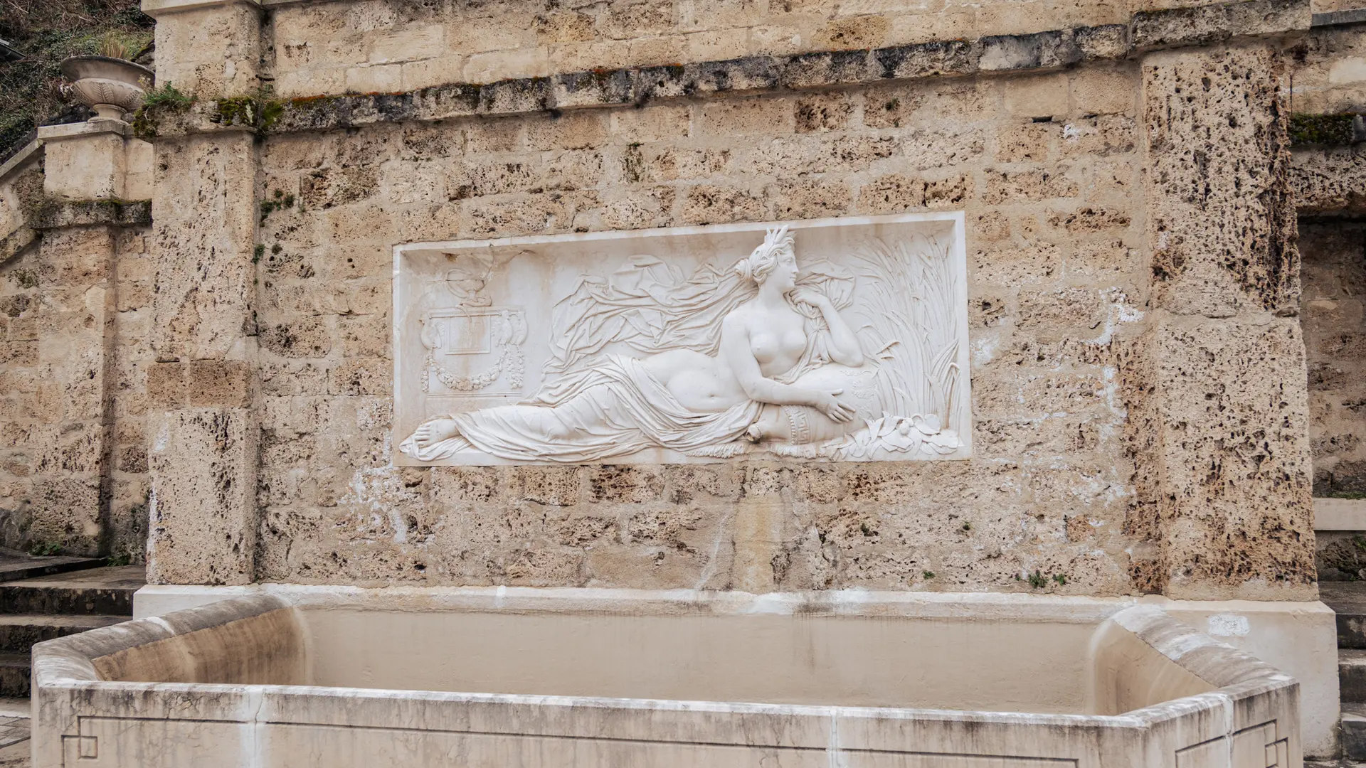 Bassin d'une fontaine surmonté d'un haut-relief de la déesse Hygie