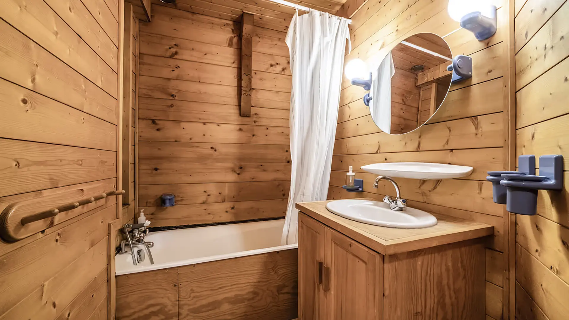Salle de bains tout en bois avec baignoire, lavabo et son meuble, miroir