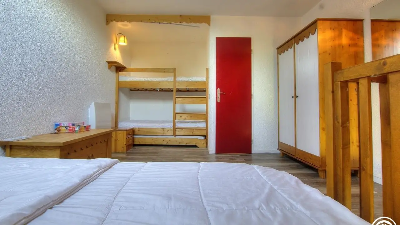 La chambre est composée d'un lit en 140*190 et deux lits en superposés en 90*190. La porte rouge donne accès à la salle de bain.
