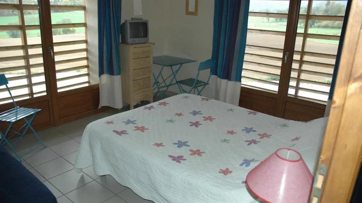 Une chambre aux grandes baies vitrées avec vue sur la campagne et les sommets du lac d'Annecy.