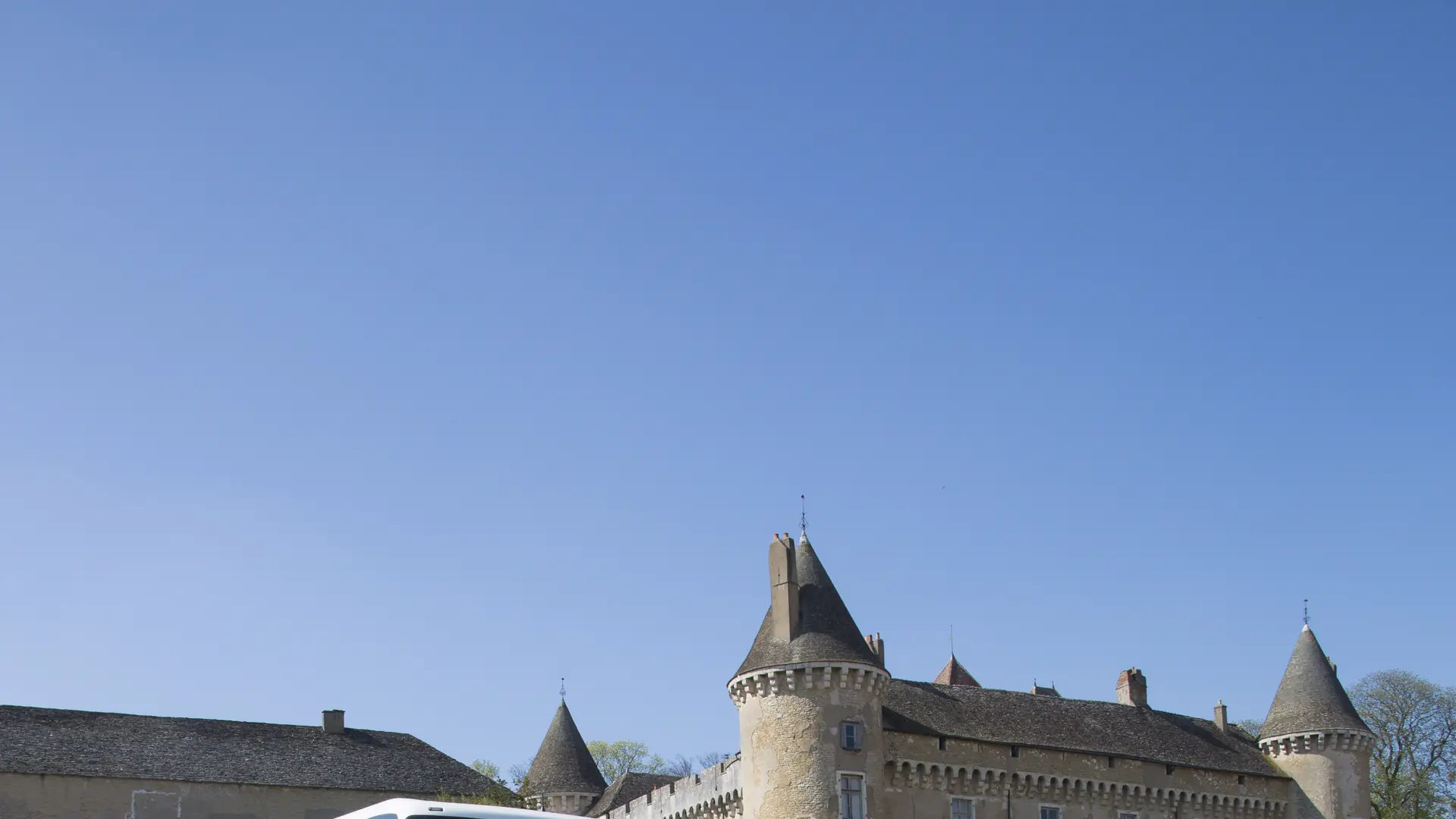 Autocar devant un château en Bourgogne et des vignes