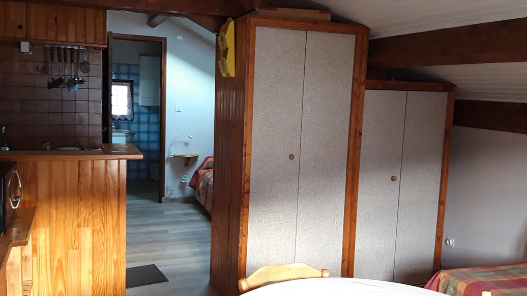 Living room with tiled kitchen area, storage space, dining table, passage to bathroom, parquet flooring