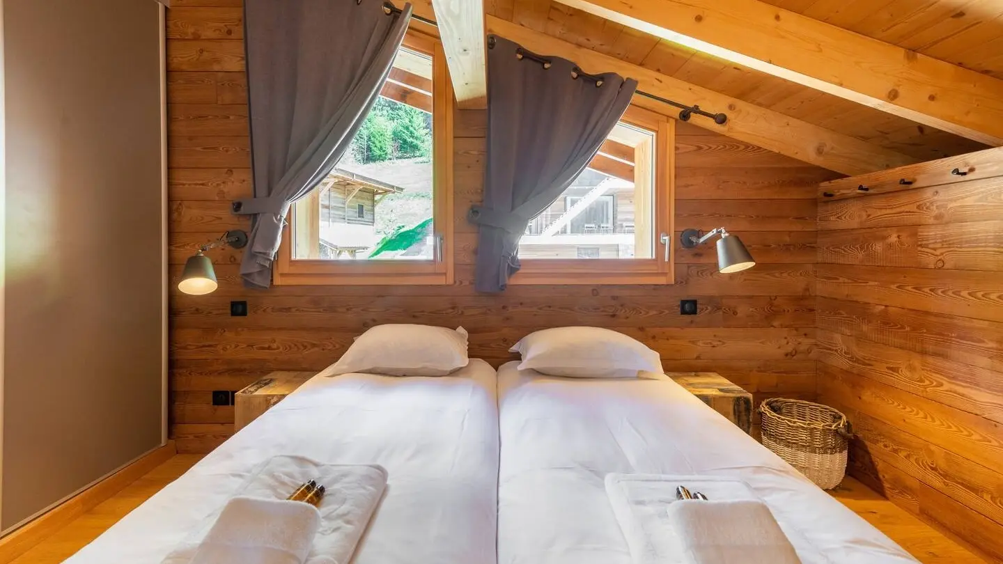 Chambre avec deux lits simples, fenêtres, poutres apparentes