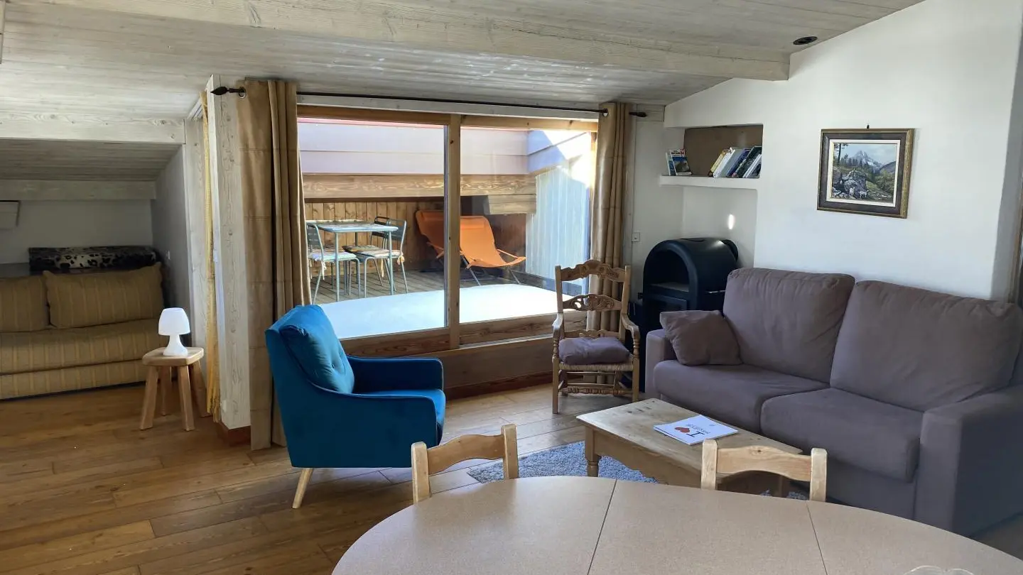 Coin repas et salon avec poêle  de bois, accès terrasse en toiture