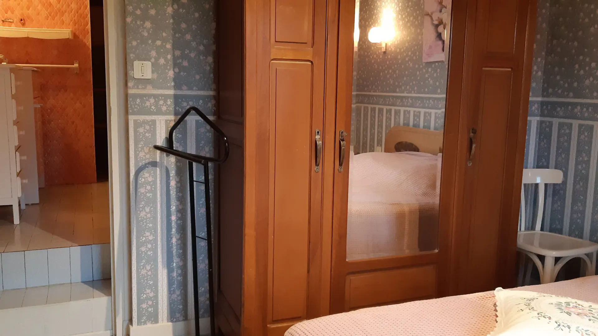 Cette chambre dispose d'un lit double, d'un espace de rangement avec une armoire miroir, et d'une chaise. Une porte donne accès à une salle de bains.