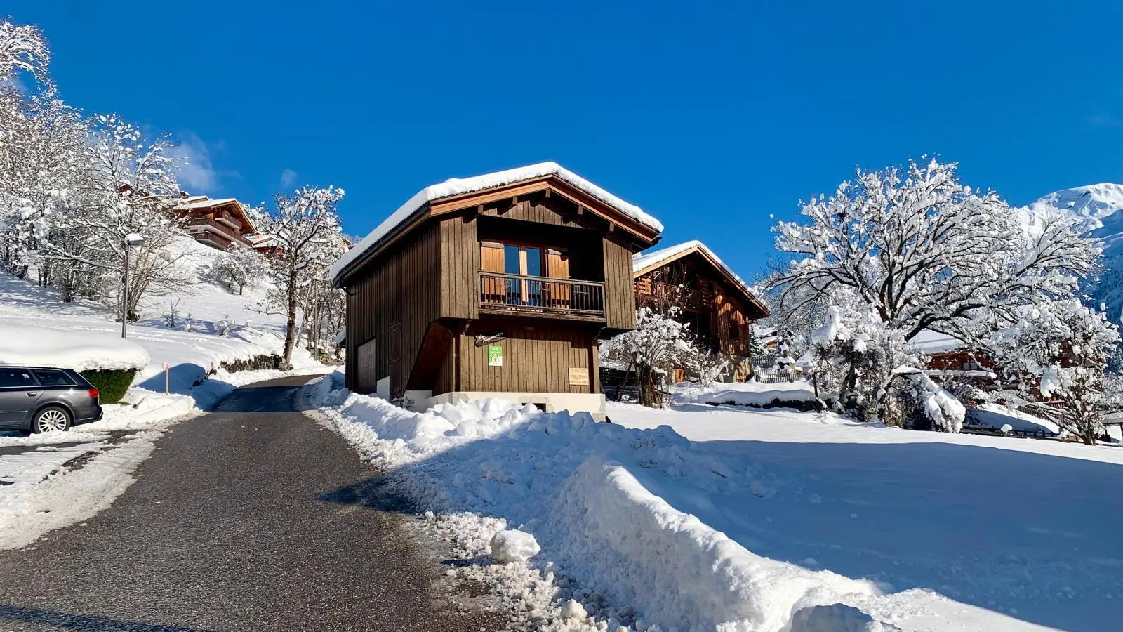 Route menant au chalet, parking privé sur la gauche du chalet et garage fermé.