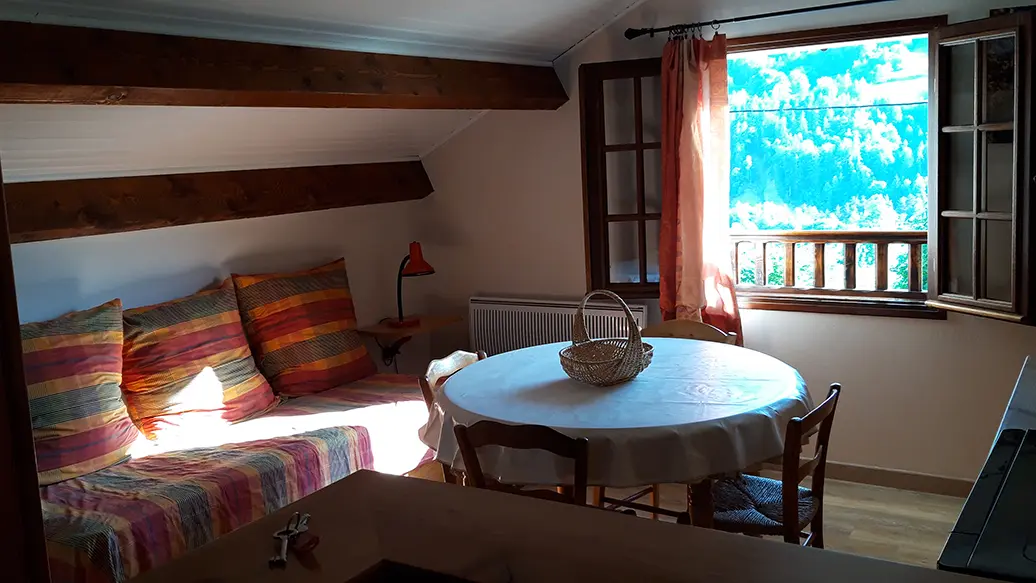 Bright attic living room with dining table, sofa, wood furniture, parquet flooring, window overlooking the mountains
